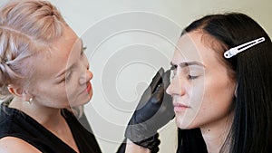 beauty saloon. the cosmetician in black rubber gloves keep a special brush and comb eyebrows. Master corrects the shape