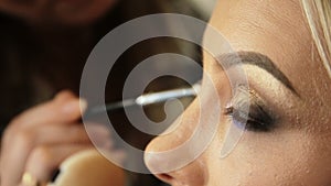 Beauty saloon Makeup artist paints the shadows on the eyes with a brush Blonde woman