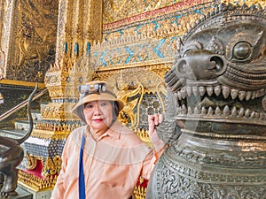 Beauty senior women with Thai lion statue in wat phrakaew Temple bangkok Thailand