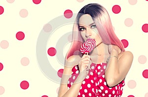 Beauty sexy model woman with pink hairstyle and beautiful makeup holding lollipop candy