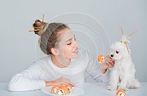 Beauty sexy woman with dog eating sushi. Sushi rolls. Fashion model girl eating Sushi with chopsticks. Perfect make up
