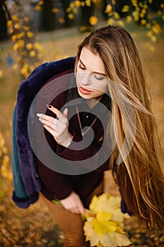 Beauty shot of fashion model woman with long red hair and big lips in autumn park enjoying nature. Close-up portrait of