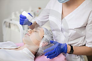 Beauty, skin care and anti-aging treatment. Face of young Caucasian woman and hands of female beautician applying