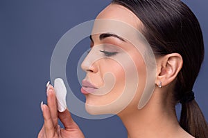 Beauty skin care. Beautiful happy woman removing face makeup using cotton pad. Close up portrait of healthy female model with nat