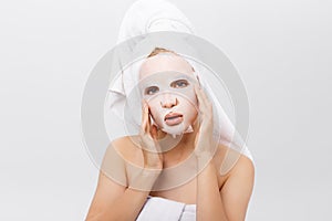 Beauty Skin Care Concept - Beautiful Caucasian Woman applying paper sheet mask on her face white background.