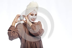 Beauty skin care concept. Young woman applying white mask to face. beautiful woman after bath with towel on her head