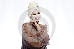 Beauty skin care concept. Young woman applying white mask to face. beautiful woman after bath with towel on her head