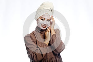 Beauty skin care concept. Young woman applying white mask to face. beautiful woman after bath with towel on her head