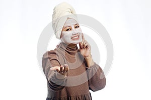 Beauty skin care concept. Young woman applying white mask to face. beautiful woman after bath with towel on her head