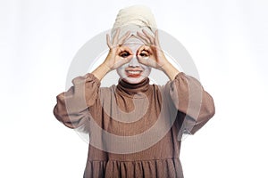 Beauty skin care concept. Young woman applying white mask to face. beautiful woman after bath with towel on her head