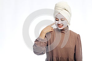 Beauty skin care concept. Young woman applying white mask to face. beautiful woman after bath with towel on her head