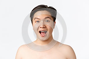 Beauty, skincare and hygiene concept. Close-up of amused and surprised asian young man standing naked over white