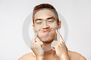 Beauty, skincare and men health concept. Headshot of funny, handsome silly asian man with naked torso, fool around over