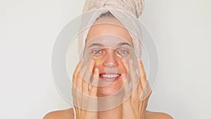 Beauty and skincare regimen. Cosmetic facial treatment. Smiling delighted woman wearing bath towel carefully places under-eye