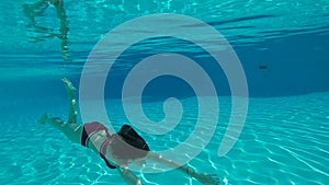 Beauty slowmotion with young woman swimming underwater in swimming pool