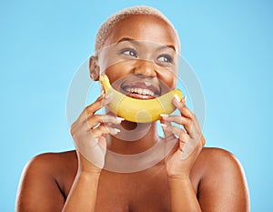 Beauty, smile and banana with a model black woman thinking on a blue background in studio. Skincare, idea and food with