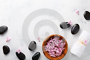 Beauty, spa background with massage stone and flowers in bowl on white table top view. Relaxation and wellness concept. Flat lay