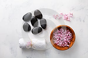 Beauty, spa background with massage stone, towel and flowers in bowl on white table top view. Relaxation and wellness concept.