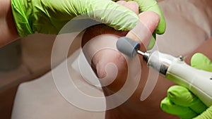 Beauty and spa concept. Closeup of feet peeling pedicure treatment using podiatry drill in the clinic. The hands of the
