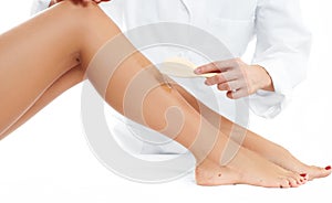 Beauty Spa. Hair removal cosmetology procedure. Beautician waxing female legs photo