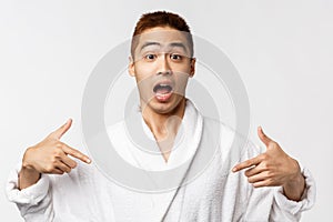 Beauty, spa and leisure concept. Portrait of surpirsed and amazed young asian man heard great news and pointing fingers