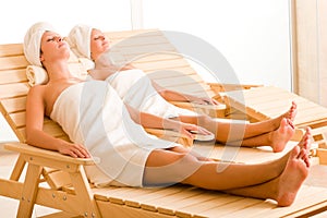 Beauty spa room two women relax sun-beds