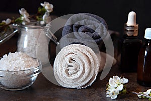 Beauty spa treatment and relax concept. Towel, sea salt and essential oils on a dark background