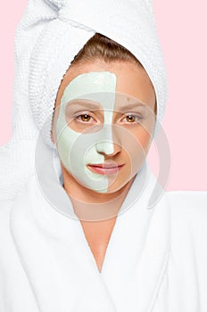 Beauty Spa. Woman applying clay mask on face. Pastel background