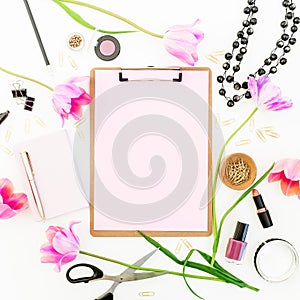 Beauty space with clipboard, notebook, cosmetics, flowers and accessories on white background. Flat lay, top view.