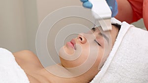 Beauty specialist makes ultrasonic peeling for female client`s face