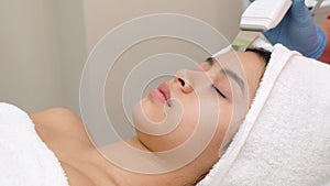 Beauty specialist makes ultrasonic peeling for female client`s face