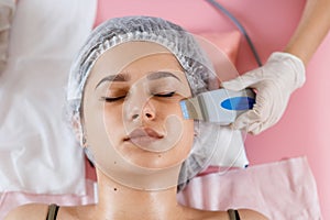 Beauty Specialist Makes Ultrasonic Peeling For Female Client& x27;s Face. Cosmetologist doing procedure of cleaning face with