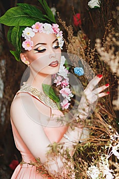 Beauty Spring girl with flowers hair. Beautiful model woman with flowers on her head. The Nature Of Hairstyle. Summer