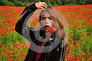 Beauty spring poppy field. Woman with poppy flower in red lips. Spring woman with red flower in mouth. Beauty, nature