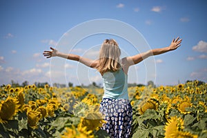 Beauty sunlit woman on yellow sunflower field Freedom and happiness concept. Happy girl outdoors