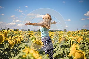 Beauty sunlit woman on yellow sunflower field Freedom and happiness concept. Happy girl outdoors