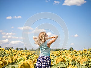 Beauty sunlit woman on yellow sunflower field Freedom and happiness concept. Happy girl outdoors