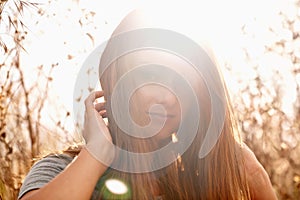 Beauty in the sunshine. Portrait of an attractive teenage girl in a field with the sun behind her.