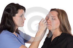 Beauty technician applying makeup on client