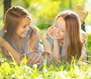 Beauty teen girls reading magazine outdoors