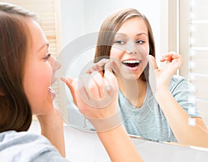 Beauty teenage girl flossing her teeth