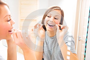 Beauty teenage girl flossing her teeth