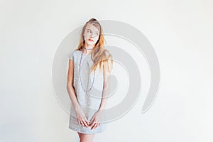 Beauty teenage girl. Portrait young teen woman in grey dress against white wall background. European woman.