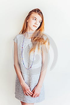 Beauty teenage girl. Portrait young teen woman in grey dress against white wall background. European woman.