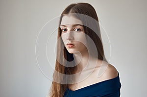 Beauty theme: portrait of a beautiful young girl with freckles on her face and wearing a blue dress on a white background in