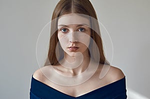 Beauty theme: portrait of a beautiful young girl with freckles on her face and wearing a blue dress on a white background in