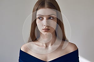 Beauty theme: portrait of a beautiful young girl with freckles on her face and wearing a blue dress on a white background in