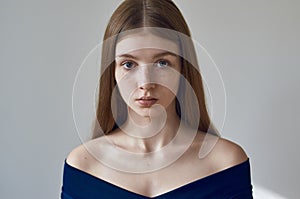 Beauty theme: portrait of a beautiful young girl with freckles on her face and wearing a blue dress on a white background in