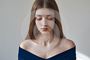 Beauty theme: portrait of a beautiful young girl with freckles on her face and wearing a blue dress on a white background in