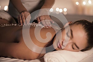 Beauty therapist pouring salt scrub on womans back